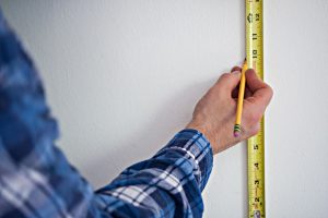 marking wall with pencil and measuring tape