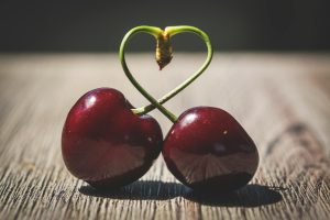 Two Red Cherries on Brown Table