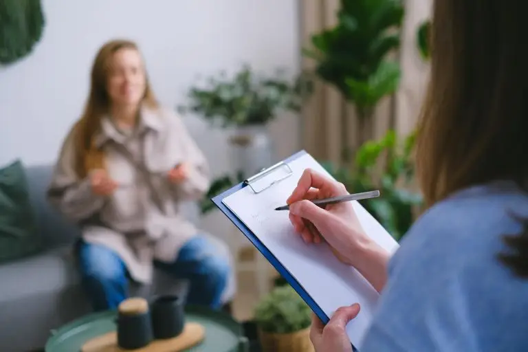 female with patient writing on clipboard