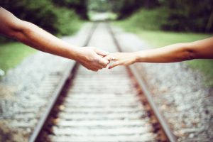 holding hands walking on train tracks