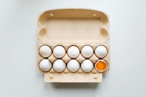 egg carton displaying eggs with one broken