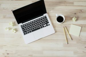 laptop and ceramic mug filled with coffee