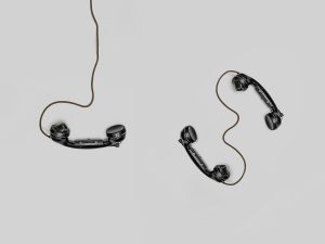 Two vintage black telephone handsets connected by cord