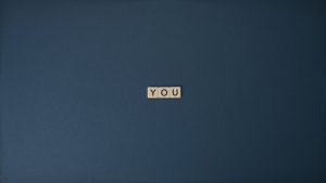 wood tiles spelling 'YOU' on a blue background