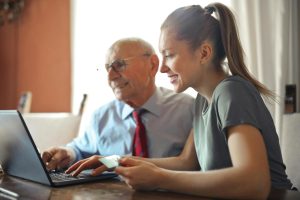 Young woman and senior man using laptop