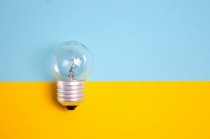 clear light bulb against a vibrant blue and yellow background