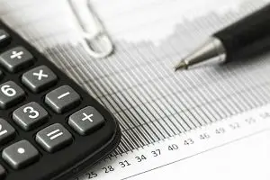Close-up of a calculator and pen on a bar graph report