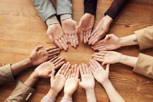 Top view of diverse hands forming a circle on a wooden table