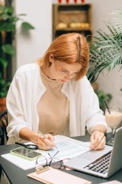 Woman analyzing financial documents using laptop