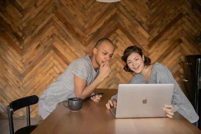 Couple smiling while using a laptop