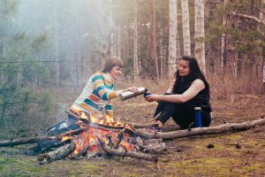 People sharing coffee near a bonfire