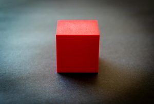 Red cube sitting on a dark surface