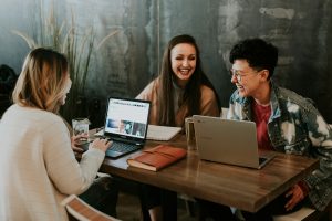 three people sitting in front of table laughing