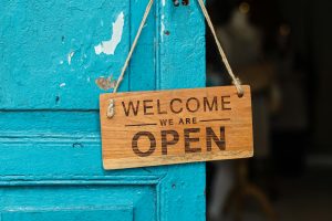 A rustic wooden welcome sign hanging on blue door