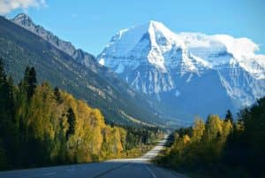 Stunning autumn scene with a road leading to a snow-capped mountain