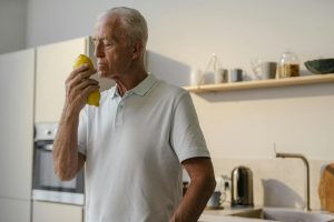 Elderly man in kitchen savoring the fresh scent of a lemon