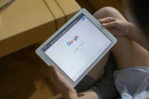 Close-up of hands holding a tablet with search page.