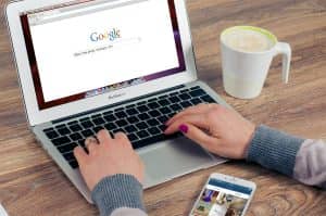 Hands typing on laptop with search engine open