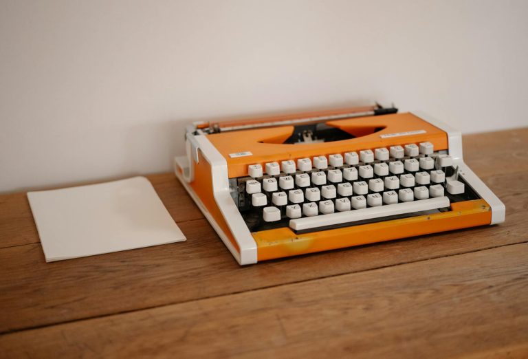 Retro orange typewriter on a wooden desk