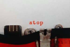 Vintage typewriter typing the word 'stop' in red on white paper.
