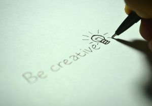 'Be creative' handwritten with a light bulb sketch on paper.