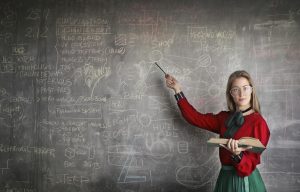 Female teacher pointing at chalkboard