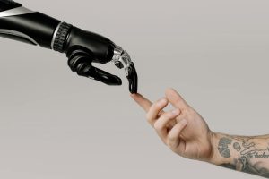 Human hand with tattoos reaching out to a robotic hand