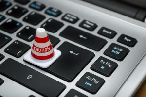 Miniature caution cone on a computer keyboard symbolizing