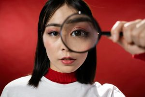 Woman holding magnifying glass over eye