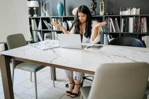 Woman sitting in an office with a laptop confused expression