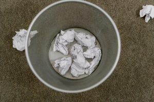 trash can filled with crumpled paper on a carpeted floor