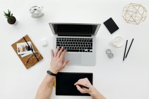Workspace person writing and researching on laptop