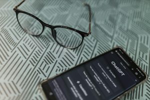 Eyeglasses next to a smartphone displaying AI app