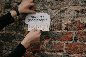 Close-up of hands paper with stars on a rustic brick wall.