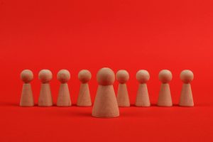 Wooden figurines arranged against a vibrant red backdrop.