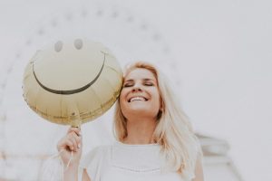 Cheerful woman holding a smiley balloon outdoors