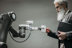 An elderly man receives a cup from a robotic arm