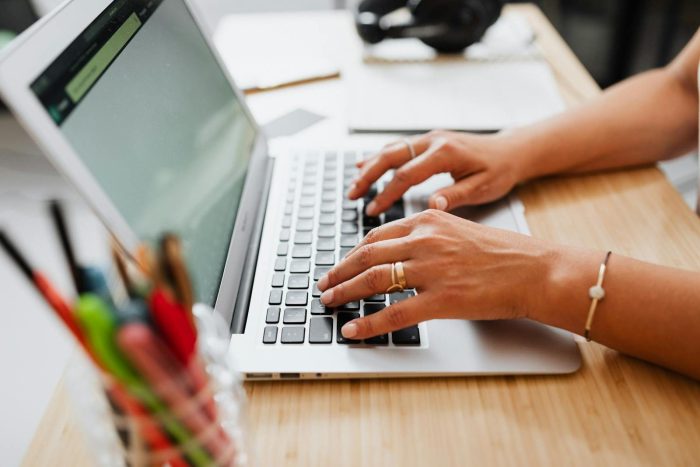 Person typing on a laptop at a wooden desk