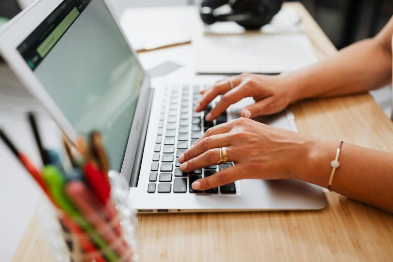 Person typing on a laptop at a wooden desk